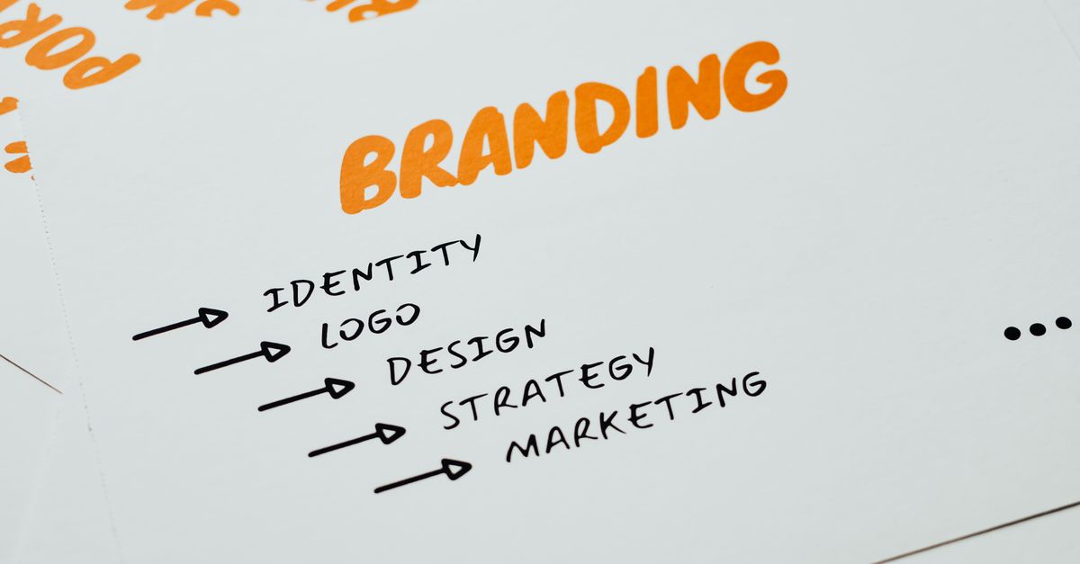 Close-up of a paper with branding, identity, design, strategy, and marketing concepts in orange and black.